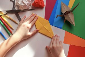 Child folding origami paper cranes